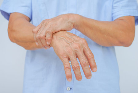 an old man support his arms which pain,numbness,weakness,paralysis concept of Guillain barre syndrome caused by autoimmune disorderの写真素材