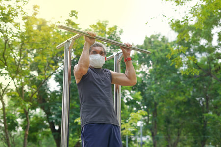 a strong old man doing exercise outdoor by hang- bar equipment in the park. concept health care in...