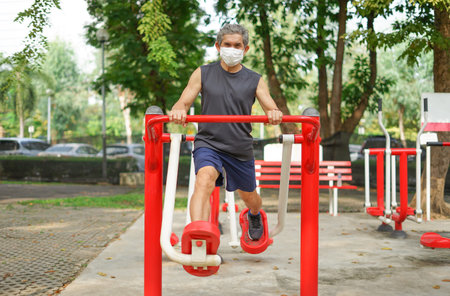 an old man doing exercise at outdoor fitness equipment in the park, concept health care in elderly people, lifestyleの写真素材