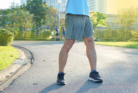 a strong senile man legs while warm up exercise in the urban park background nature atmosphere in the morning sunshine.concept lifestyle self health care in elderly peopleの写真素材