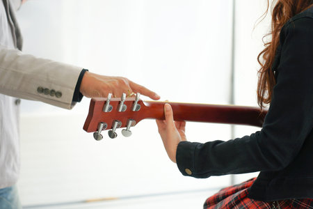 instructor teaching the girl to play guitar in music academy(selective focus), music class study...
