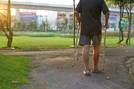 back view, a senior man on using a walker walk forward among nature atmosphere in the morning sunshine, concept lifestyle, self health rehabilitationの写真素材