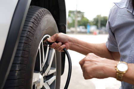 a traveller senior man inflate car tire to ensure to drive, concept risk management and safety to use a carの写真素材