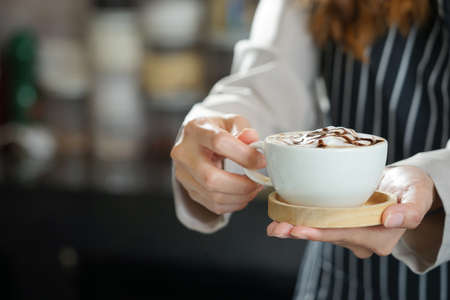 barista hand holding a cup of hot coffee to serving customerの写真素材