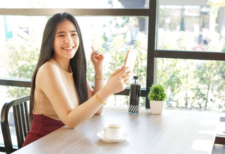 young asian woman with mobile phone sittng casually in the coffee shop