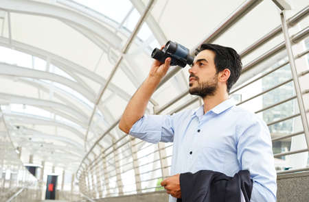young businessman with binoculars looking for opportunity to develop business in the futureの写真素材
