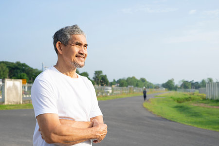 portrait runner asian man standing with arms crossed on the road, happy senior man workout in the...