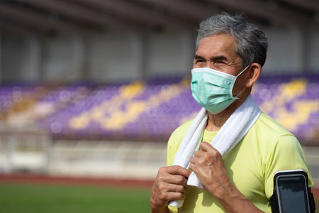 portrait senior man in sportswear wears protective face mask standing in the stadium