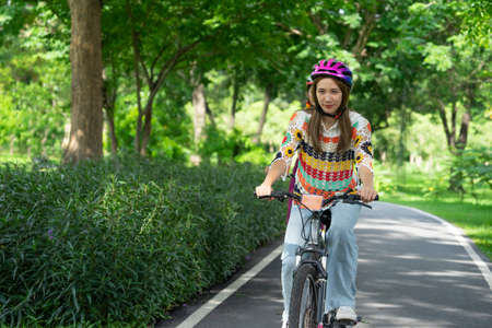 portrait young attractive healthy woman wear helmet cycling happily in the park. concept people life, lifestyle, activity, travel etcの写真素材