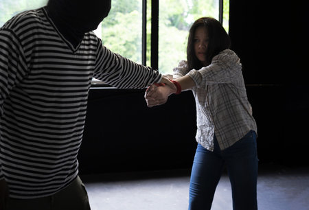 woman victim being tied in the dark room and pulling against with a robber, concept for women, violent, crime, victim, hostageの写真素材