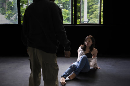 scene of asian woman trying to escape a robber or rapist is raping her in an abandoned house,...