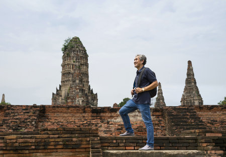 A happy senior man is walking up the old bricks stairs to visit ancient historical park, concept elderly retired man lifestyle,freedom,travel,ecotourism,quality of lifeの写真素材