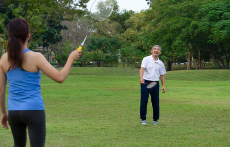 cheerful senior man and daughter playing badminton in the park, concept elderly people lifestyle, health care, wellness, family relationshipの写真素材