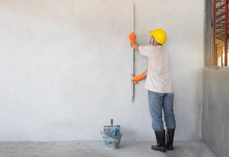 worker holding aluminium cement screed  or triangle trowel plastering wall for building house