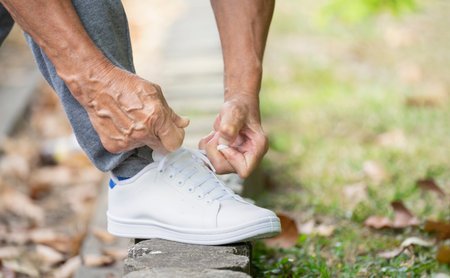 senior man tying shoelace getting ready for exercise, concept of preventing the risk of falls in the elderlyの写真素材