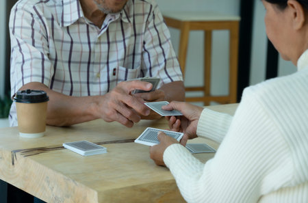 active senior pensioners playing cards game together, concept elderly retired people entertainment,encourages social interaction,help memory retentionの写真素材