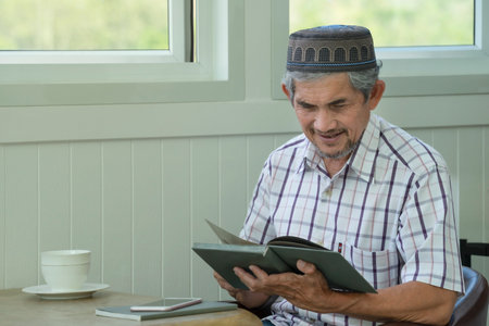 muslim senior man wearing hat concentrate on reading a book, concept elderly lifestyle,hobbiesの写真素材
