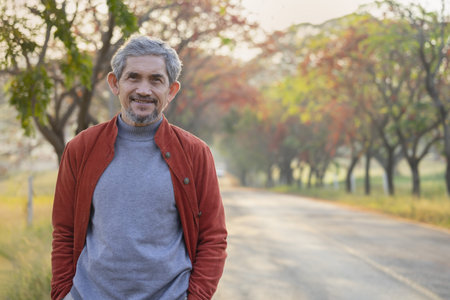 portrait senior man with grey hair and beard standing beside the street, happy elderly pensioner...