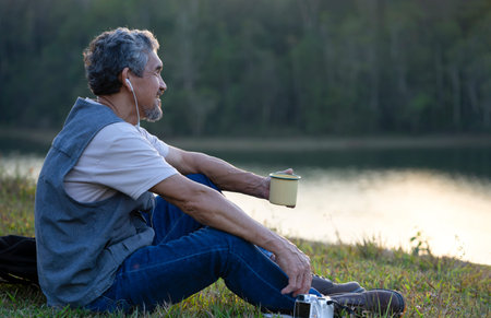 healthy mature man resting by the reservoir, listening music, smiling and looking forward,happy...