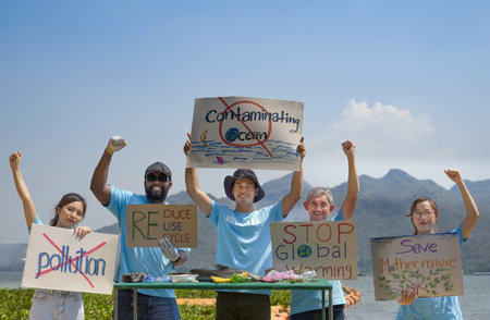 group of volunteers holding environmental campaign signs standing by the river, dead fish and rubbish on table. concept of environmental conservation, save planet, earth day in Aprilの写真素材