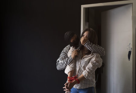 robber kidnapping hostage woman,tied her hands with red rope, blocked her mouth from making a...