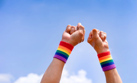 man hands wears lgbtq colorful rainbow wristband doing hand fist up into the sky,support or respect of lgbtq+ community equality movement,love,rights,freedom,tolerance,concept lgbt happy pride monthの写真素材