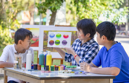 middle age art teacher enjoy teaching the young teens student at school art club outdoors, asian female teacher helps teenage pupil painting in art classの写真素材