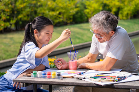 teen girl enjoy painting with grandfather in the summer garden, concept family lifestyle,relationship,raising teen, the love of a familyの写真素材