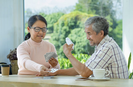 joyful senior couple enjoy playing cards game together, concept elderly pensioner lifestyle, entertainment, recreation, encourages social interaction, help memory retentionの写真素材