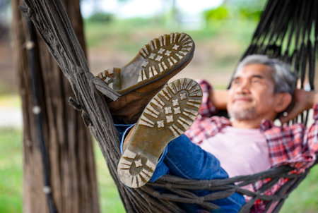 a male legs in boots on rope hammock background nature, happy mature man lying on a hammock at resort garden on summertime,concept of people holidays,travel,camping,adventureの写真素材