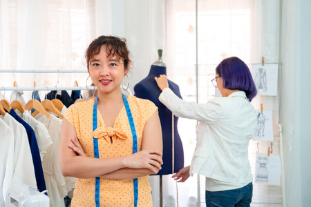 portrait a smiling young female dressmaker standing arms crossed,looking at camera in her clothing business studio,concept of clothing design,tailoring,business,industryの写真素材