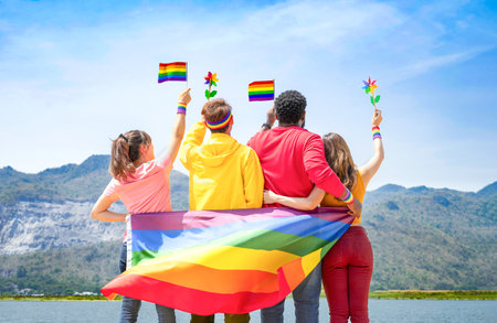 group of diverse lgbtq friends wearing colorful clothes, standing side by side, smiling and holding lgbt flags waving in the air, concept of lgbt community equality movement, lgbt happy pride monthの写真素材
