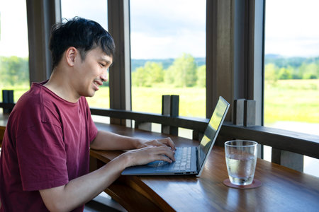 young asian man working remotely on internet online over laptop on vacation,take a break in cafe on...
