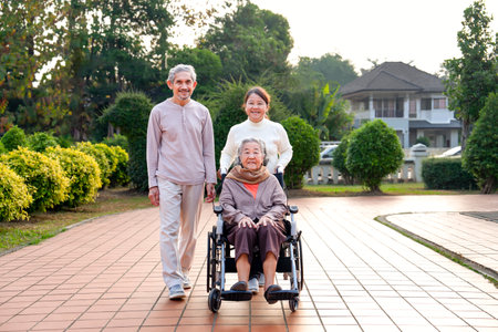 concept of family lifestyle, relationship,senior grandma sitting on wheelchair,smiling,daughter and son in law walking with her in the city parkの写真素材