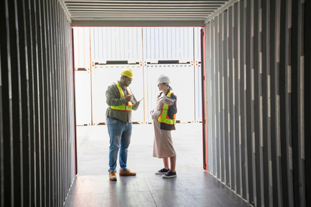 caucasian pregnancy female holds digital tablet and a fat man worker in front of opened box container,woman engineer manager inspecting the cargo,shipping company workers working at terminal portの写真素材