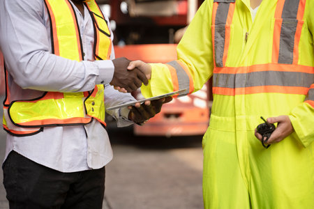 black african man holding digital tablet and asian man holding walkie talkie,handshake together for success of cooperation between cargo inspection and containers movement transport at terminal portの写真素材