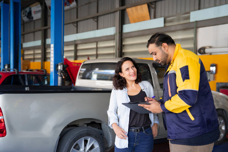 asian auto mechanic man holding clipboard paper and explain details of the car maintenance and repair to the owner,concept of garage serviceの写真素材