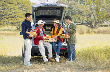 happy family,father,a daughter and sons checking  harvested fruits and talking behind a car in...