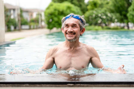 portrait happy elderly man with goggles in swimming pool,healthy asian senior male enjoying his summer vacation at resort,senior pensioner people travel and relaxingの写真素材