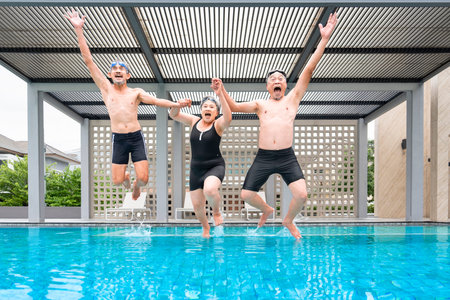 group of cheerful asian senior jumping and playing in the pool,elderly people enjoy summer time at...