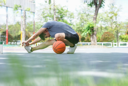 basketball player stretching at outdoors stadium,athlete warming up before play gameの写真素材