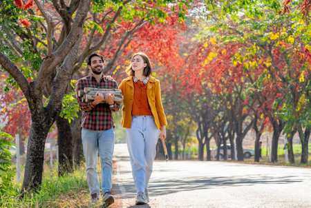 young caucasian family,a female holding axe,a man carrying firewood while walking home after working in farm ,concept of seasonal harvesting in autumnの写真素材