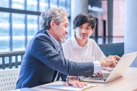 A young asian man sitting and conversation with advisor teacher,professor giving advice university student with laptop computerの写真素材