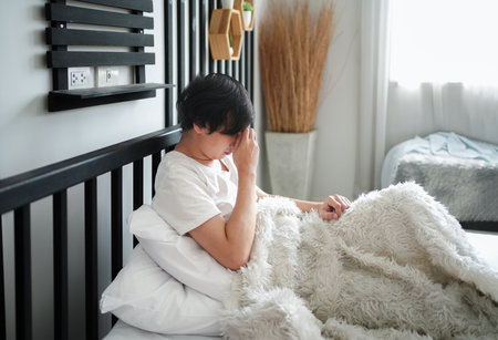 A young insomnia man waking up on bed,concept of people tired,fatigue,inadequate sleepの写真素材