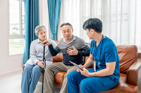 asian senior couple giving a health interview to home visiting nurse,young male nurse using tablet to give advice on practice,concept of elderly health care,home health nursing,home health careの写真素材