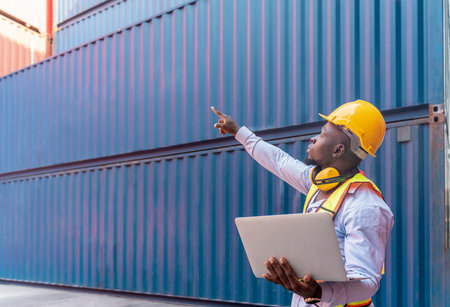 african man in safety gear and hardhat using tablet computer,control loading container box,foreman...