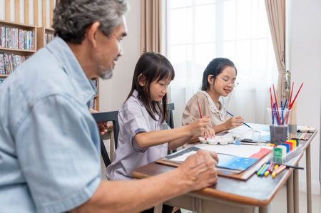 teen girls enjoy drawing watercolors with a senior experienced teacher,elementary students learning new skill of art during school breakの写真素材
