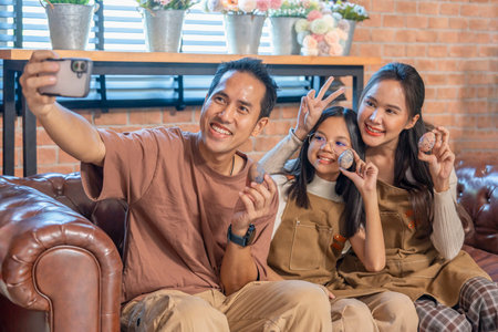 cozy family enjoy painting easter eggs with a daughter,taking selfie together indoors at homeの写真素材