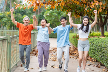 bonding happy asian family relationship,hands holding each other walking in the park,looking at camera,healthcare,exercisingの写真素材