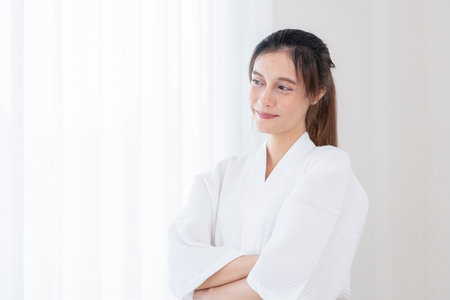 portrait young pretty woman in bathrobe standing in spa room with copy space for textの写真素材